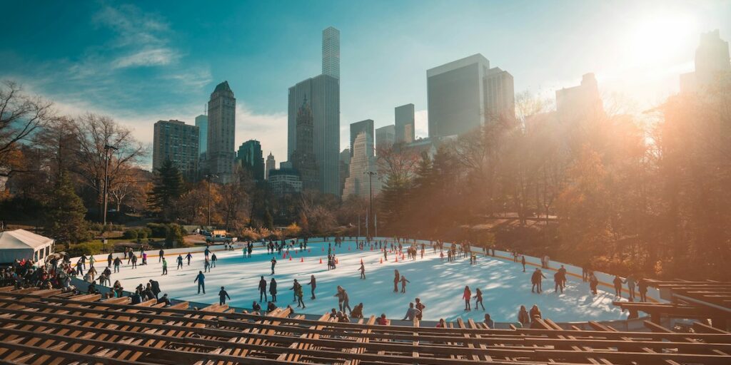 The winter ice skating rink in Central Park, with the cinematic skyline of Manhattan in the background.